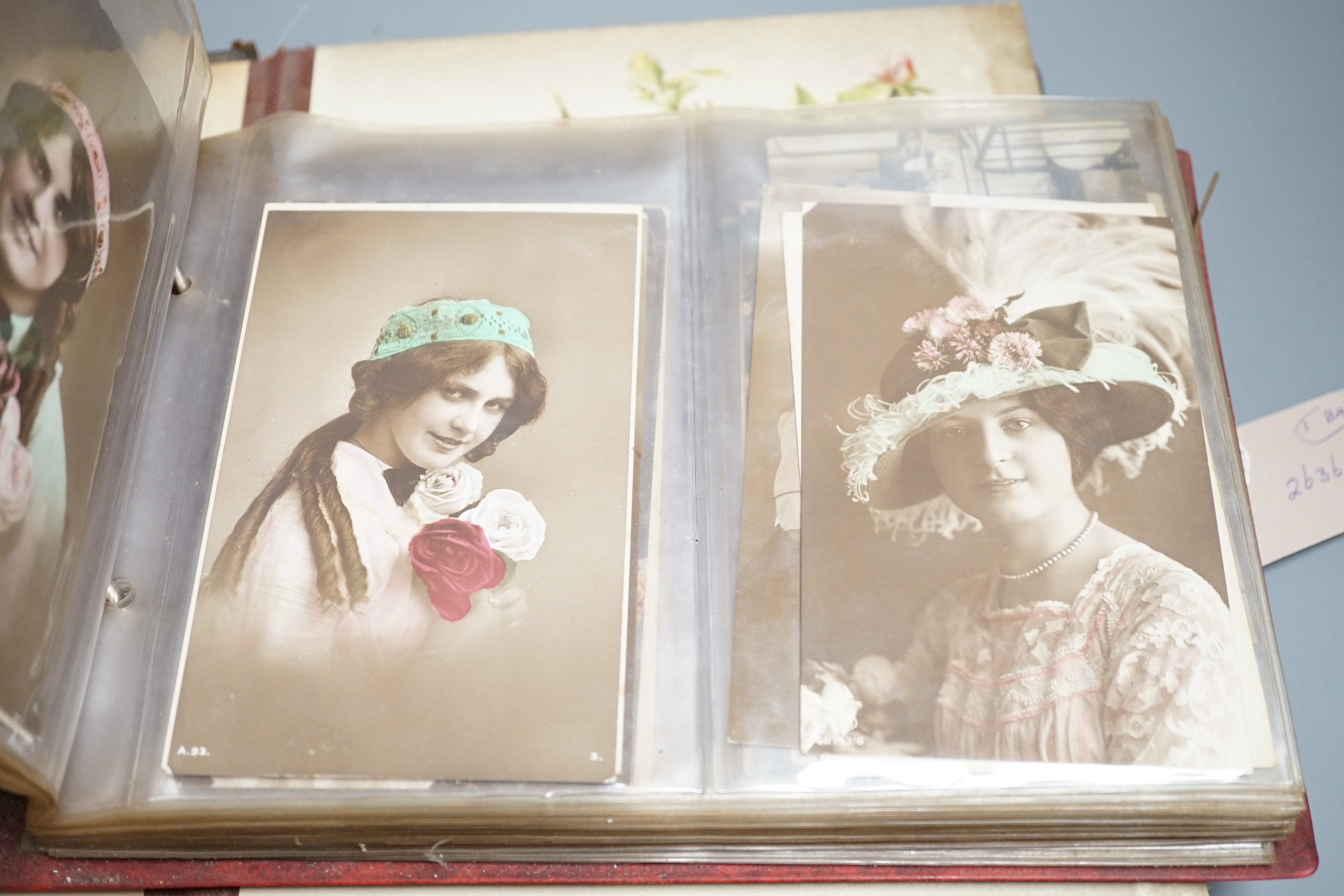 An early 20th century postcard collection in two albums and an empty late Victorian leather photo album